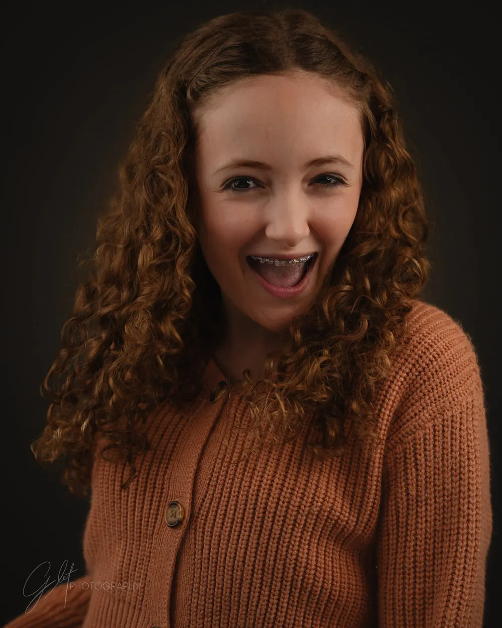 A young woman in a chunky rust-colored knit cardigan — texture doing the work a pattern would