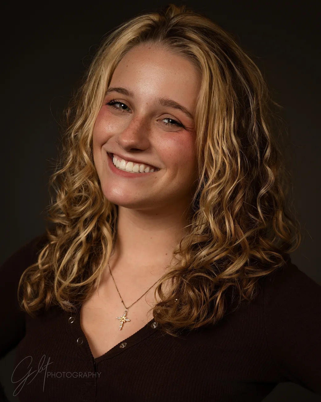 A studio headshot — blonde curls, easy smile