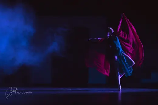 A dancer trailing magenta silk through stage fog