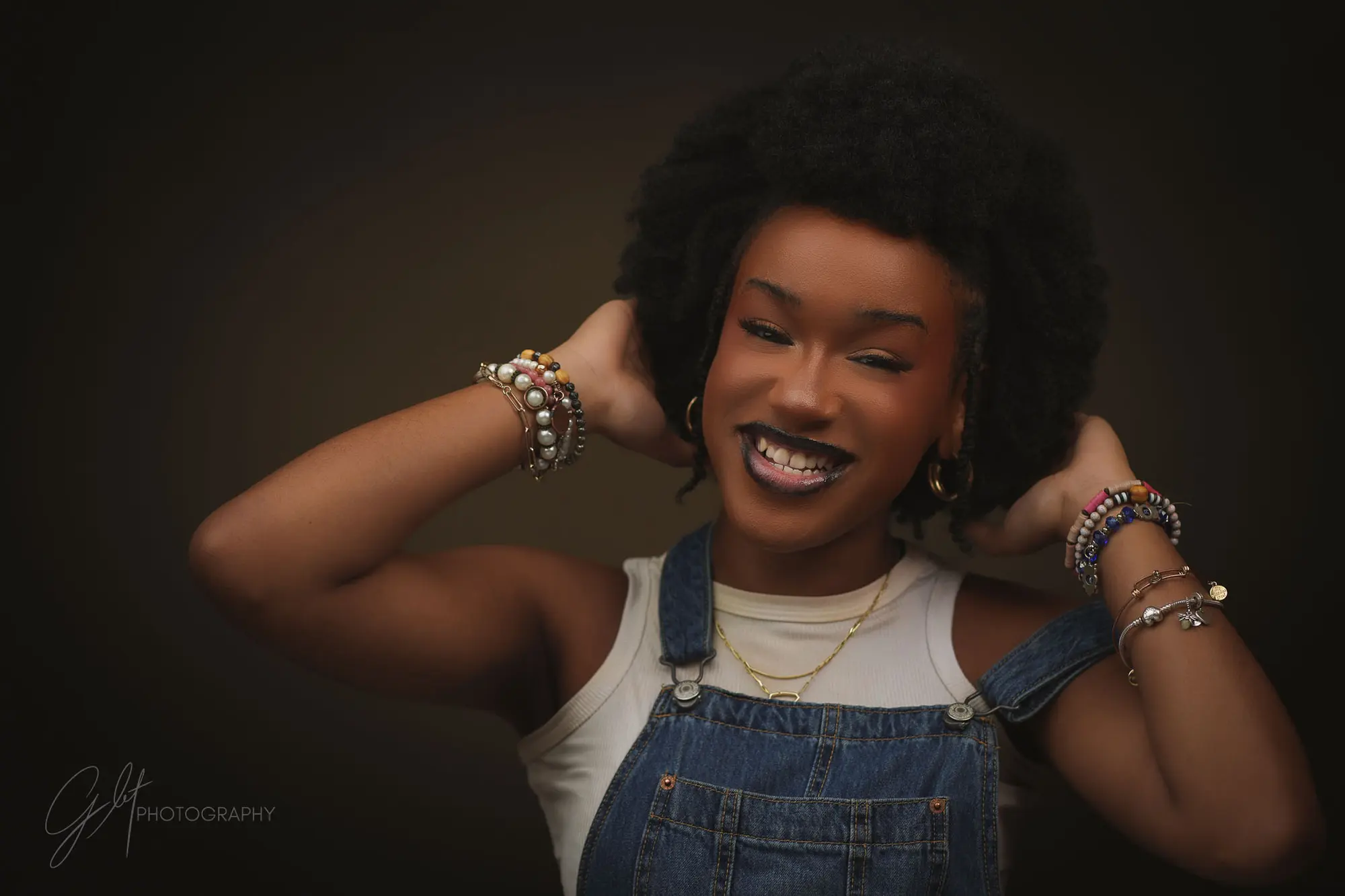 The same woman in overalls, hand in her hair, laughing